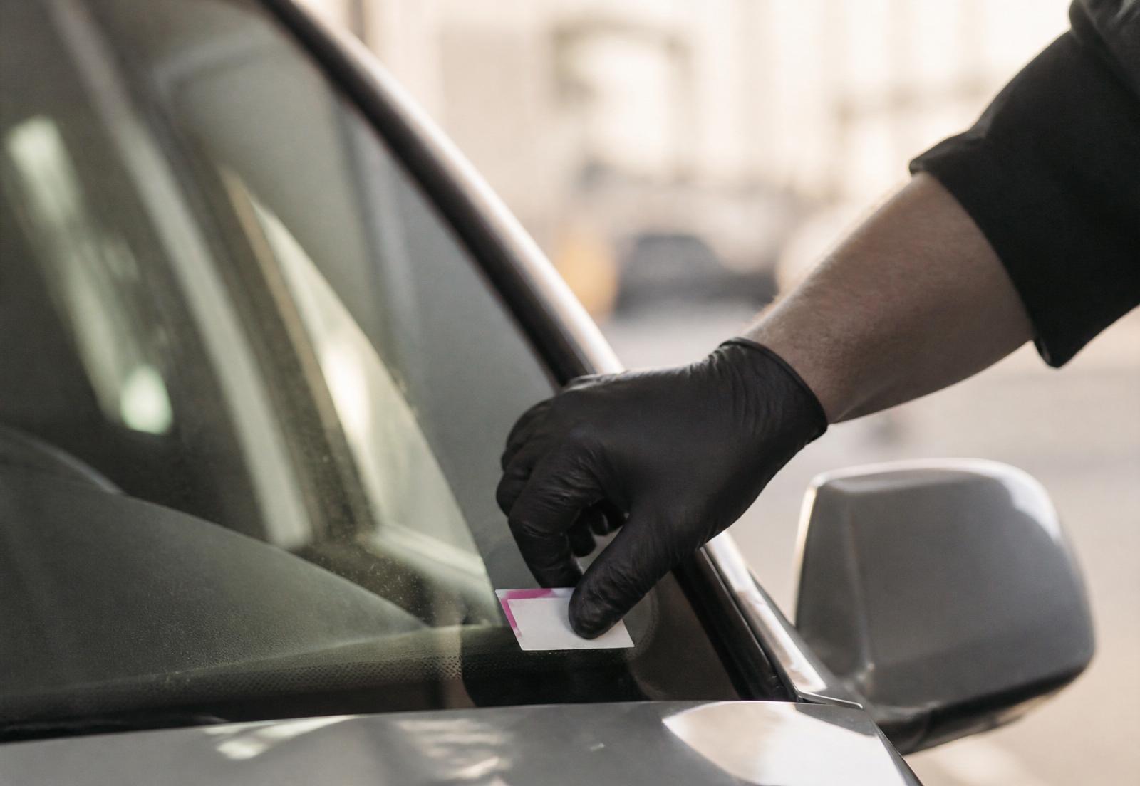 Authorised inspector applying an eSafety compliance sticker to a vehicle windshield during a mobile inspection in Sydney